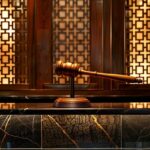 a powerful gavel hovers above a sleek, reflective surface, symbolizing justice and the protection of rights in a modern legal setting, illuminated by warm, focused lighting.