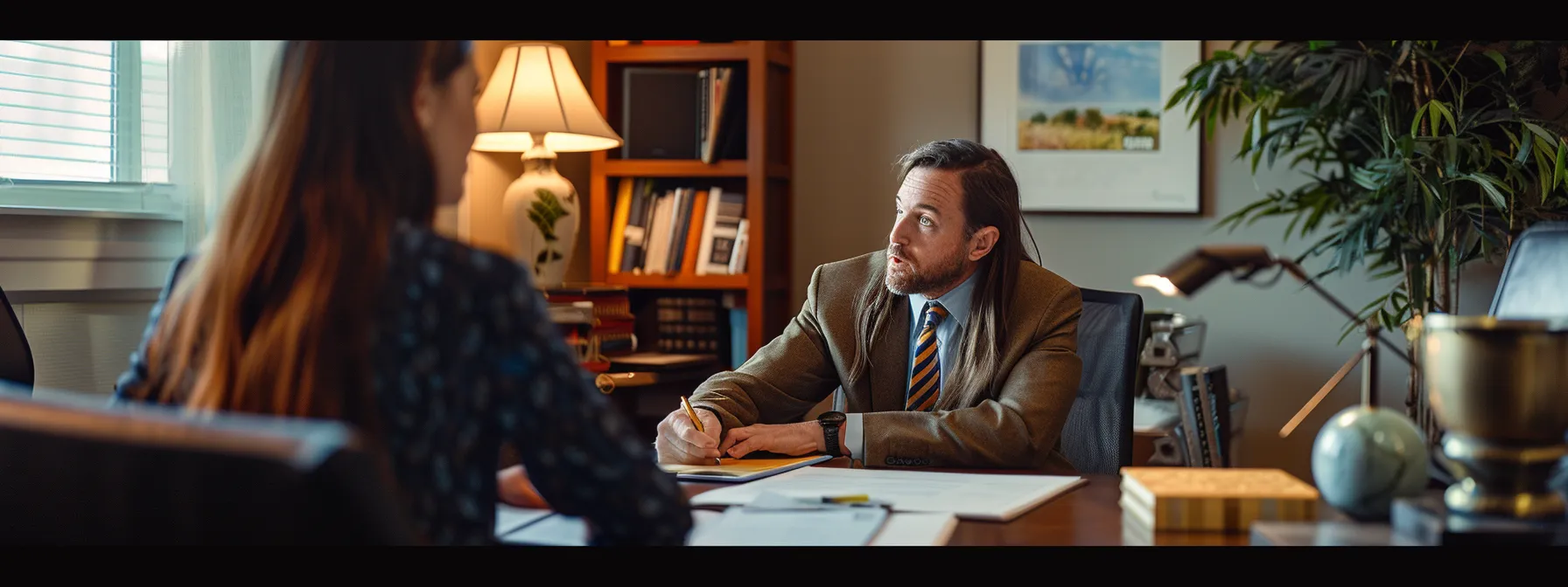 a somber-looking individual sits across from a compassionate experienced lawyer, discussing legal strategies and reviewing crucial case documentation in a tastefully decorated office.