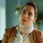 a woman in a neck brace surrounded by legal documents and a laptop, talking to a lawyer in a modern office setting.