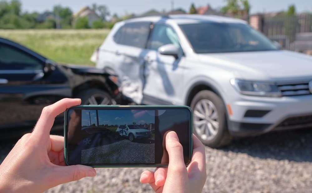 A woman taking photographs of a damaged car after accident as evidence