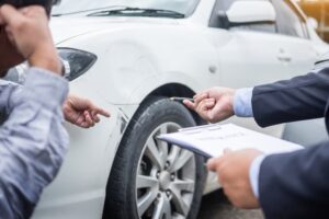 Insurance adjuster examining car after accident