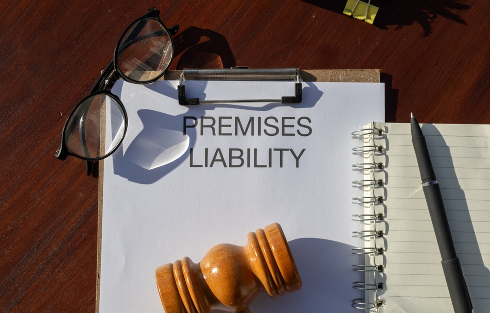 Clipboard labeled “Premises Liability” beside a gavel, glasses, and a notepad.