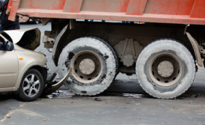 Passenger car wedged under the rear of a dump truck after a crash.