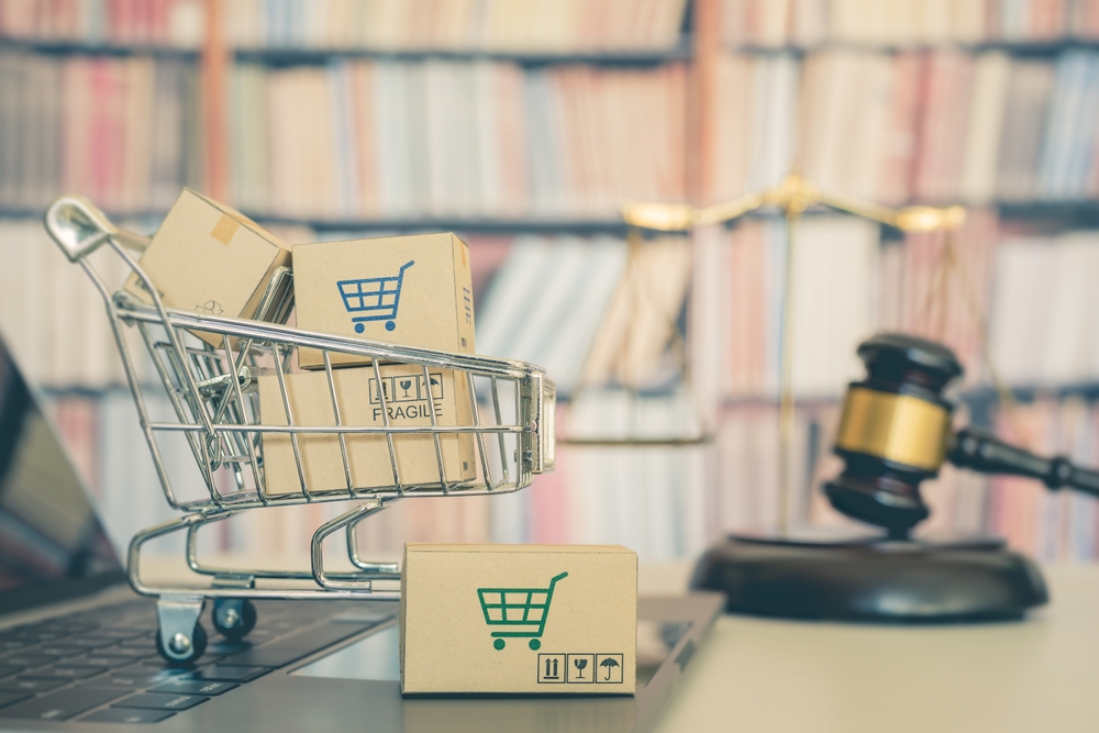 Miniature shopping cart with boxes beside a gavel and legal scales, symbolizing product liability lawsuits.