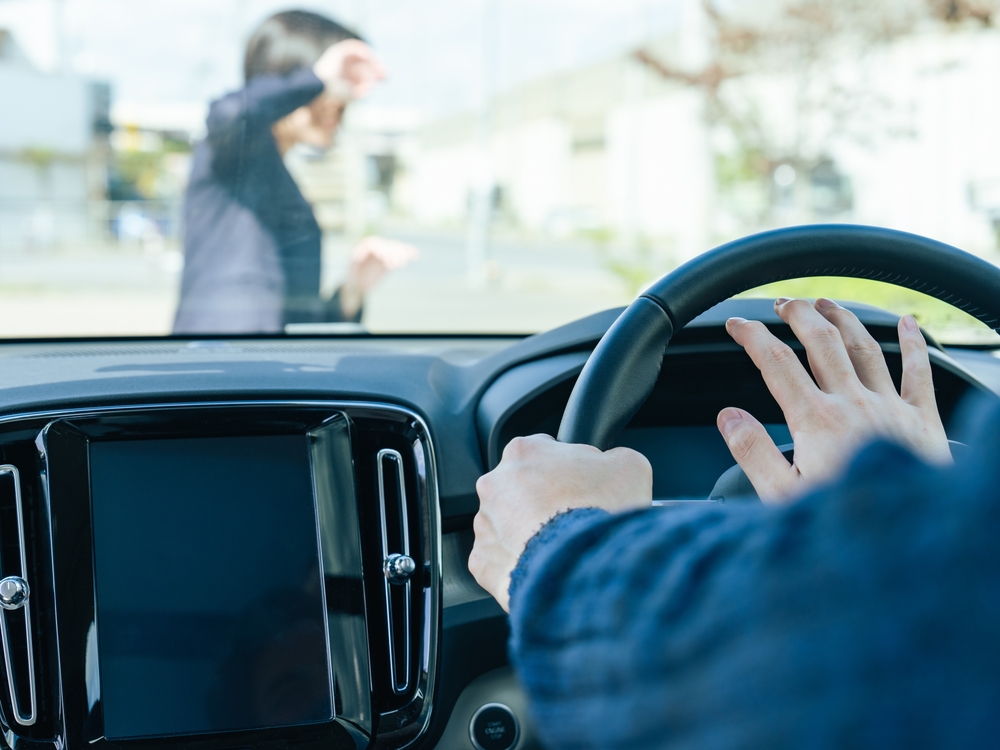 Driver braking as a pedestrian walks in front of the vehicle at a crosswalk.