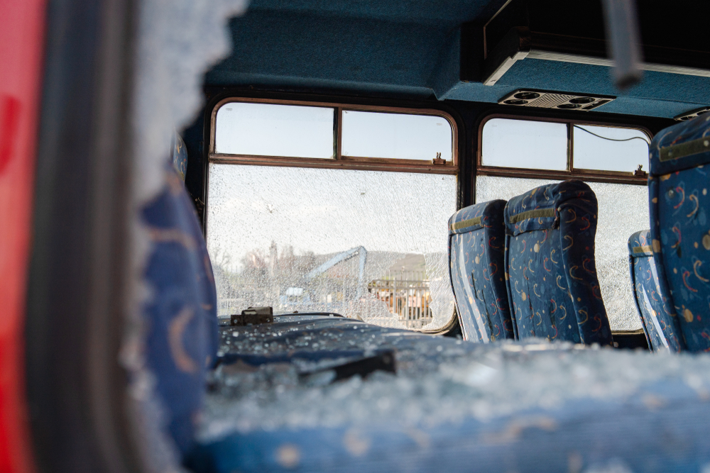 Interior of a damaged bus with shattered windows and broken glass following a Houston bus accident.