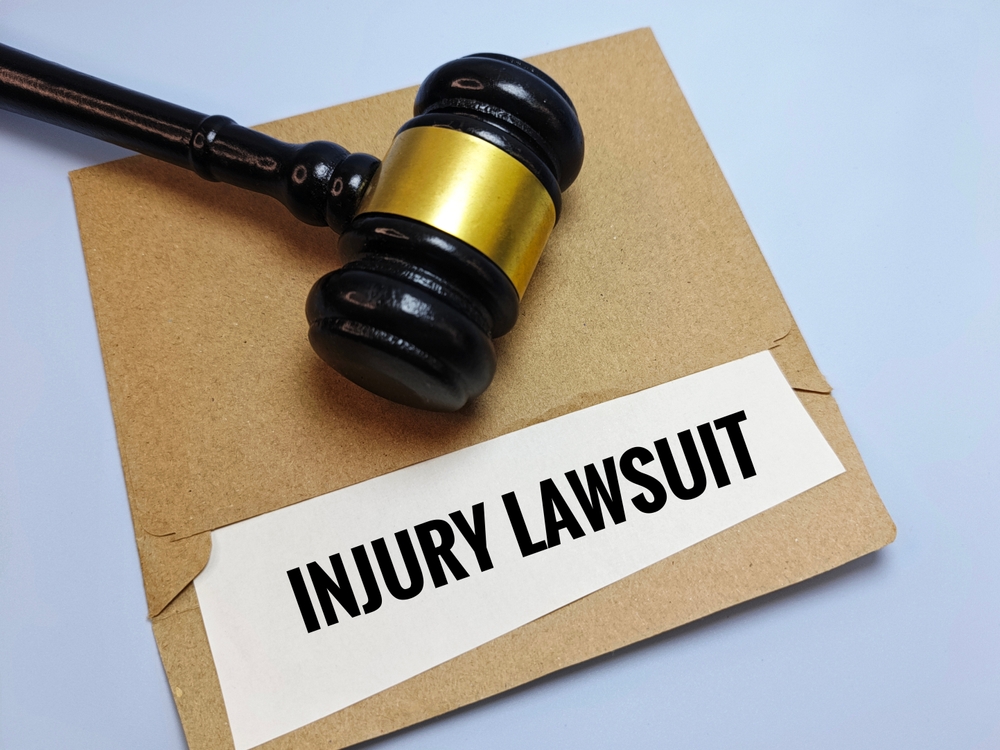 Gavel resting on an envelope labeled Injury Lawsuit, representing personal injury lawsuit steps.