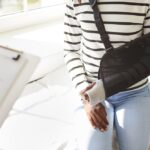 Injured woman with arm in a medical sling speaking to a doctor after an accident